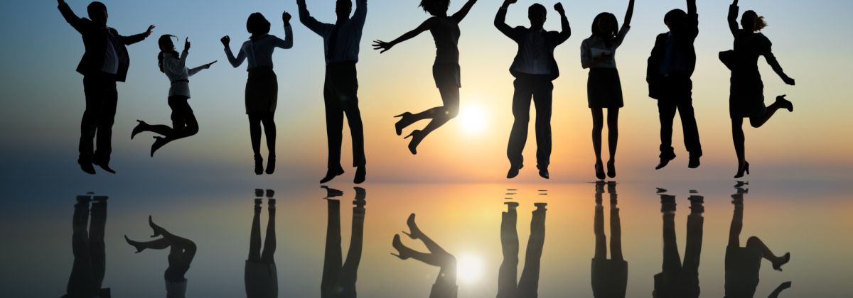 Jumping people silhouetted against a sunset on a shiny floor, like wet sand.